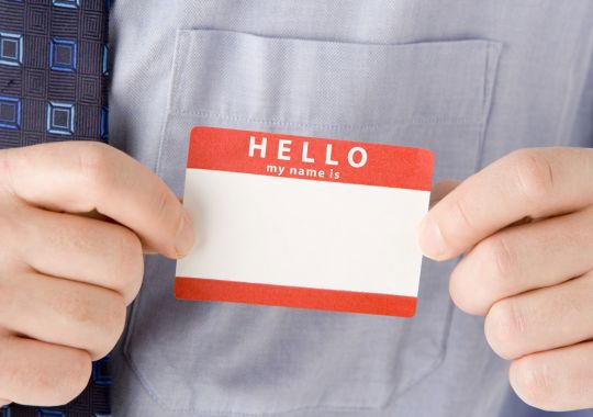 איש מחזיק תג שם שלו עם חולצה מכופתרת ועניבה