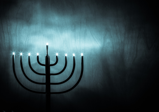 ציור של חנוכיה שחורה דולקת עם שמונה נרות ושמש על רקע כחול ושחור