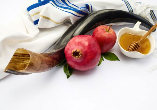 רימון, תפוח, קערה עם דבש, שופר וטלית עם פסים תכלת והכול על רקע לבן