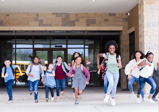 קבוצה של ילדים רצים מהבית ספר החוצה לכיוון הבית