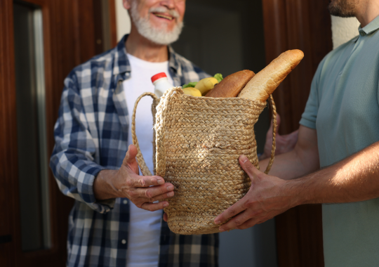 איש מבוגר עם חולצת משבצות מקבל סלסלה עם מצרכים